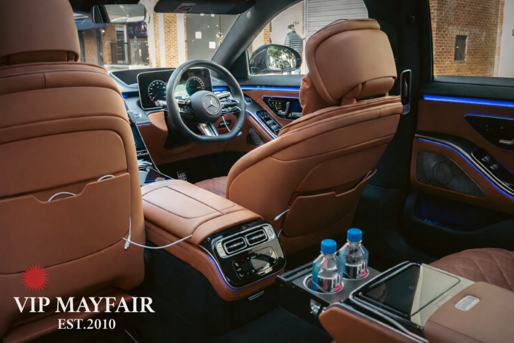 Luxury Mercedes-Benz S-Class interior prepared for a VIP Mayfair heliport transfer, featuring bottled water and a phone charger ready for the client.