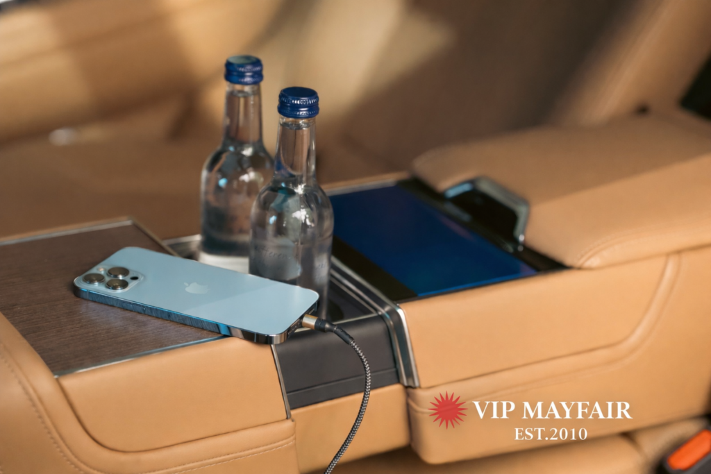 Luxury Range Rover rear interior with leather seats, charging cable and two glass water bottles, showcasing VIP Mayfair chauffeur comfort.